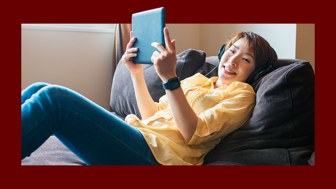 Jovem deitada confortavelmente assistindo com seu tablet